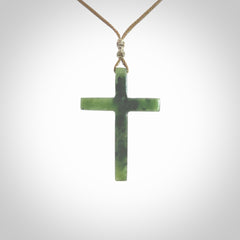 Hand carved jade cross. Made from New Zealand jade. Christian cross for sale online.This picture shows a green jade cross suspended on a fine, plaited cord. The cross is hand carved jade cross. Made from New Zealand jade. Christian cross for sale online.