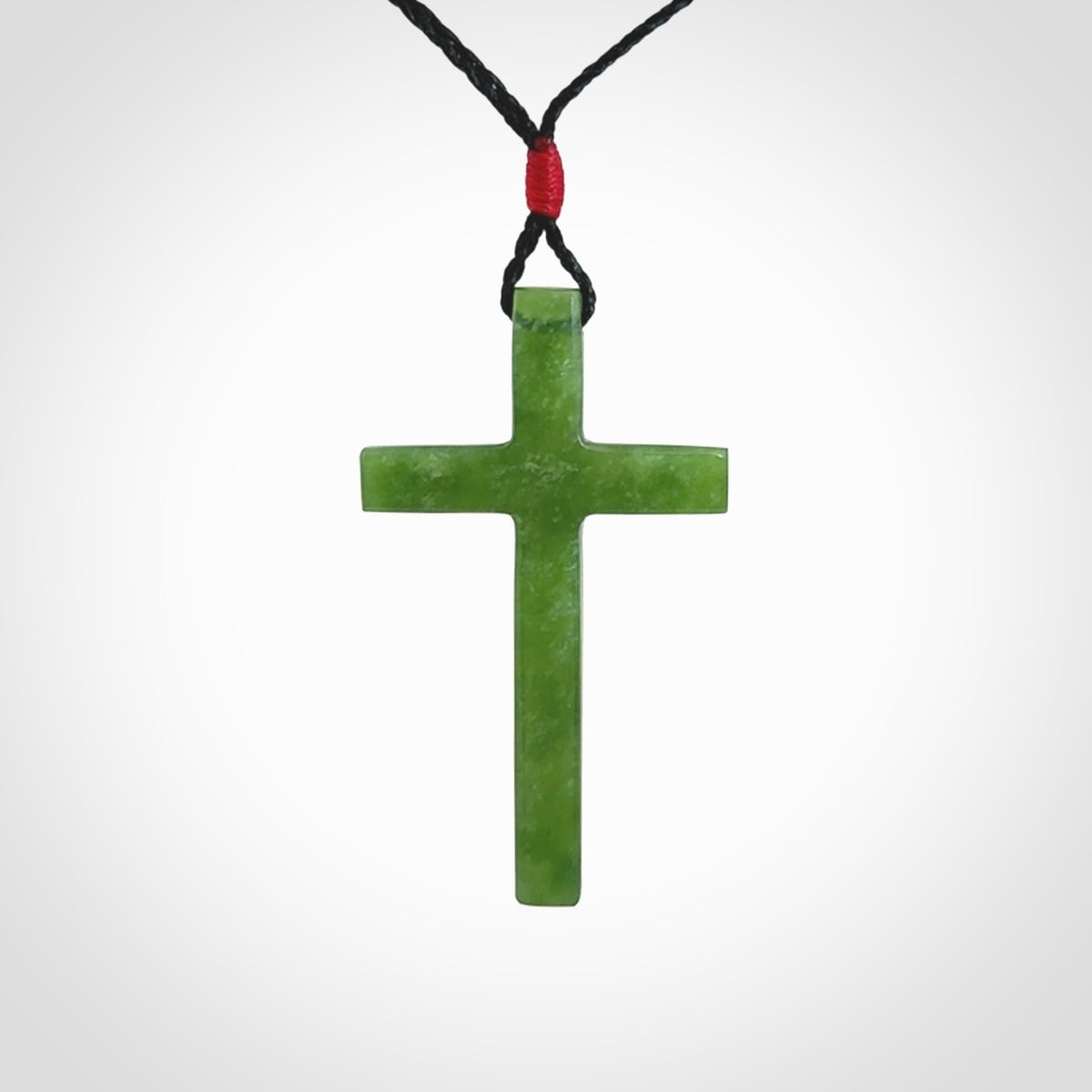 Hand carved jade cross. Made from New Zealand jade. Christian cross for sale online.This picture shows a green jade cross suspended on a fine, plaited cord. The cross is hand carved jade cross. Made from New Zealand jade. Christian cross for sale online.