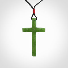 Hand carved jade cross. Made from New Zealand jade. Christian cross for sale online.This picture shows a green jade cross suspended on a fine, plaited cord. The cross is hand carved jade cross. Made from New Zealand jade. Christian cross for sale online.