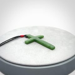 Hand carved jade cross. Made from New Zealand jade. Christian cross for sale online.This picture shows a green jade cross suspended on a fine, plaited cord. The cross is hand carved jade cross. Made from New Zealand jade. Christian cross for sale online.