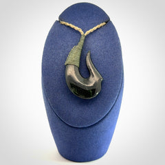 This photo shows a New Zealand Tangiwai hook, or matau, pendant. The plaited cord is khaki and the length can be adjusted.