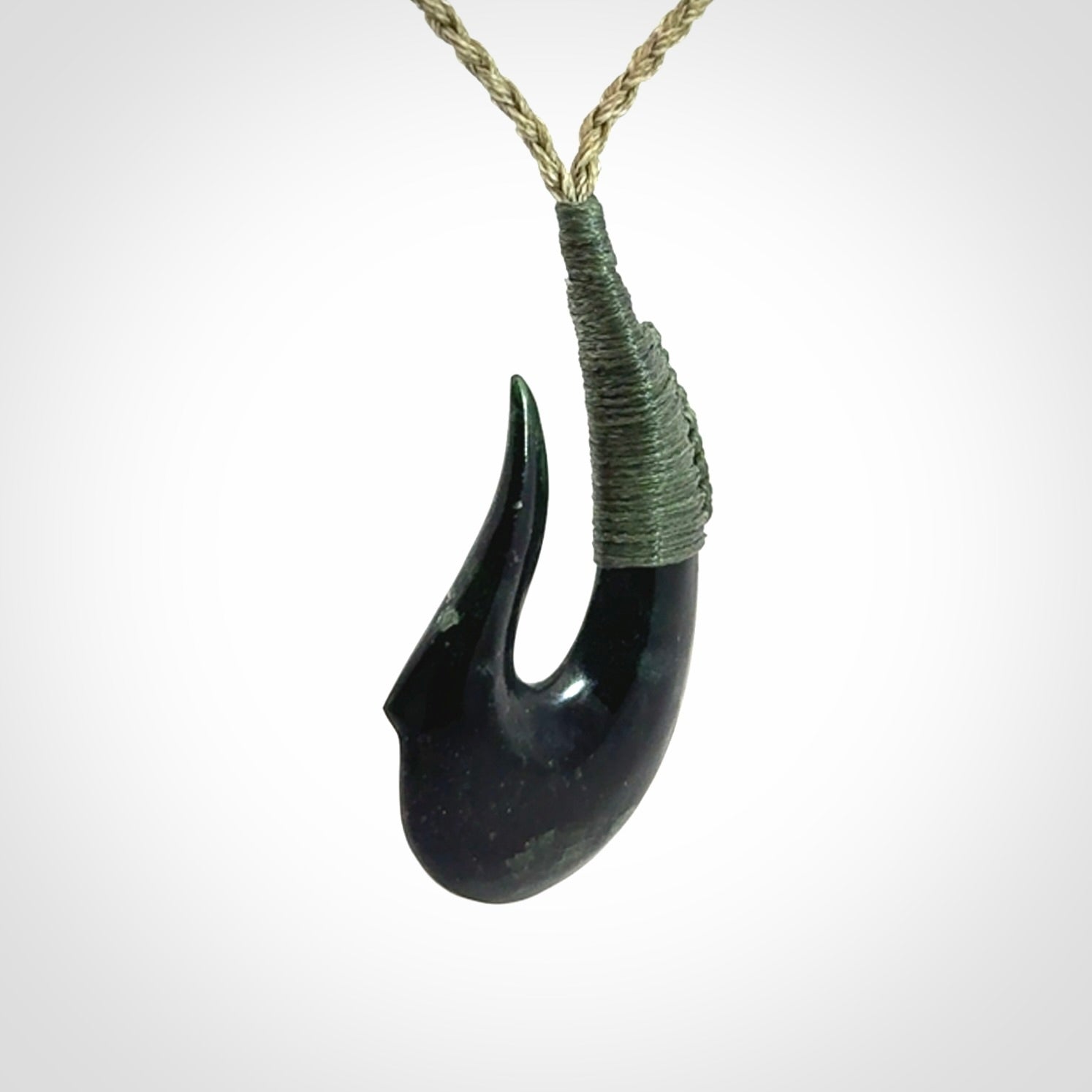 This photo shows a New Zealand Tangiwai hook, or matau, pendant. The plaited cord is khaki and the length can be adjusted.