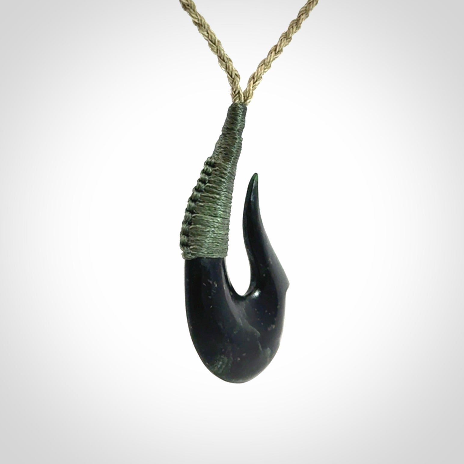 This photo shows a New Zealand Tangiwai hook, or matau, pendant. The plaited cord is khaki and the length can be adjusted.