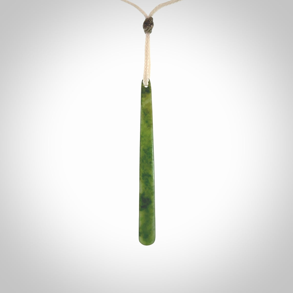 This picture shows a hand carved jade drop pendant by Ric Moor. The jade is a wonderful light, semi-translucent, green. It is suspended from a meringue coloured adjustable cord. Delivery is free worldwide.