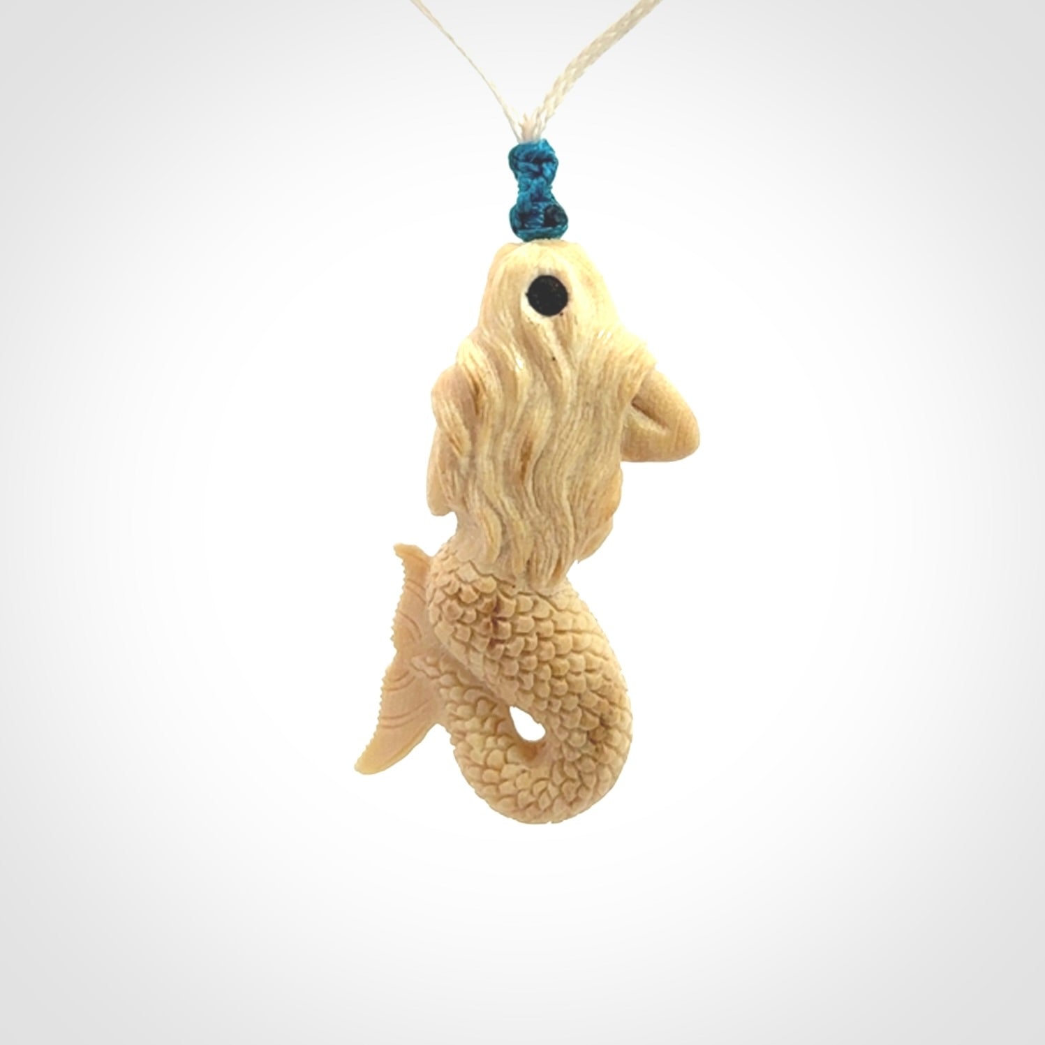 This photo shows a photo of a mermaid pendant. It is handcarved from a beautifully creamy piece of woolly mammoth tusk. It is suspended on an adjustable cord.