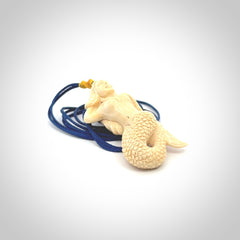 This photo shows a photo of a mermaid pendant. It is handcarved from a beautifully creamy piece of woolly mammoth tusk. It is suspended on an adjustable cord.
