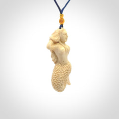 This photo shows a photo of a mermaid pendant. It is handcarved from a beautifully creamy piece of woolly mammoth tusk. It is suspended on an adjustable cord.