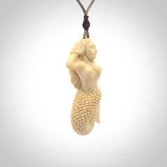 This photo shows a photo of a mermaid pendant. It is handcarved from a beautifully creamy piece of woolly mammoth tusk. It is suspended on an adjustable cord.