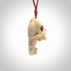 A hand carved SKULL pendant made from deer antler with Pyrope Garnet eyes. This is a work of art carved in deer antler, bone. We deliver this pendant to you on a plaited juicy red and passion red cord. Delivery with Express Courier is included in the price.