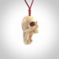 A hand carved SKULL pendant made from deer antler with Pyrope Garnet eyes. This is a work of art carved in deer antler, bone. We deliver this pendant to you on a plaited juicy red and passion red cord. Delivery with Express Courier is included in the price.