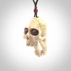 A hand carved SKULL pendant made from deer antler with Pyrope Garnet eyes. This is a work of art carved in deer antler, bone. We deliver this pendant to you on a plaited black cord. Delivery with Express Courier is included in the price.