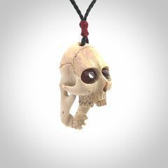 A hand carved SKULL pendant made from deer antler with Pyrope Garnet eyes. This is a work of art carved in deer antler, bone. We deliver this pendant to you on a plaited black cord. Delivery with Express Courier is included in the price.