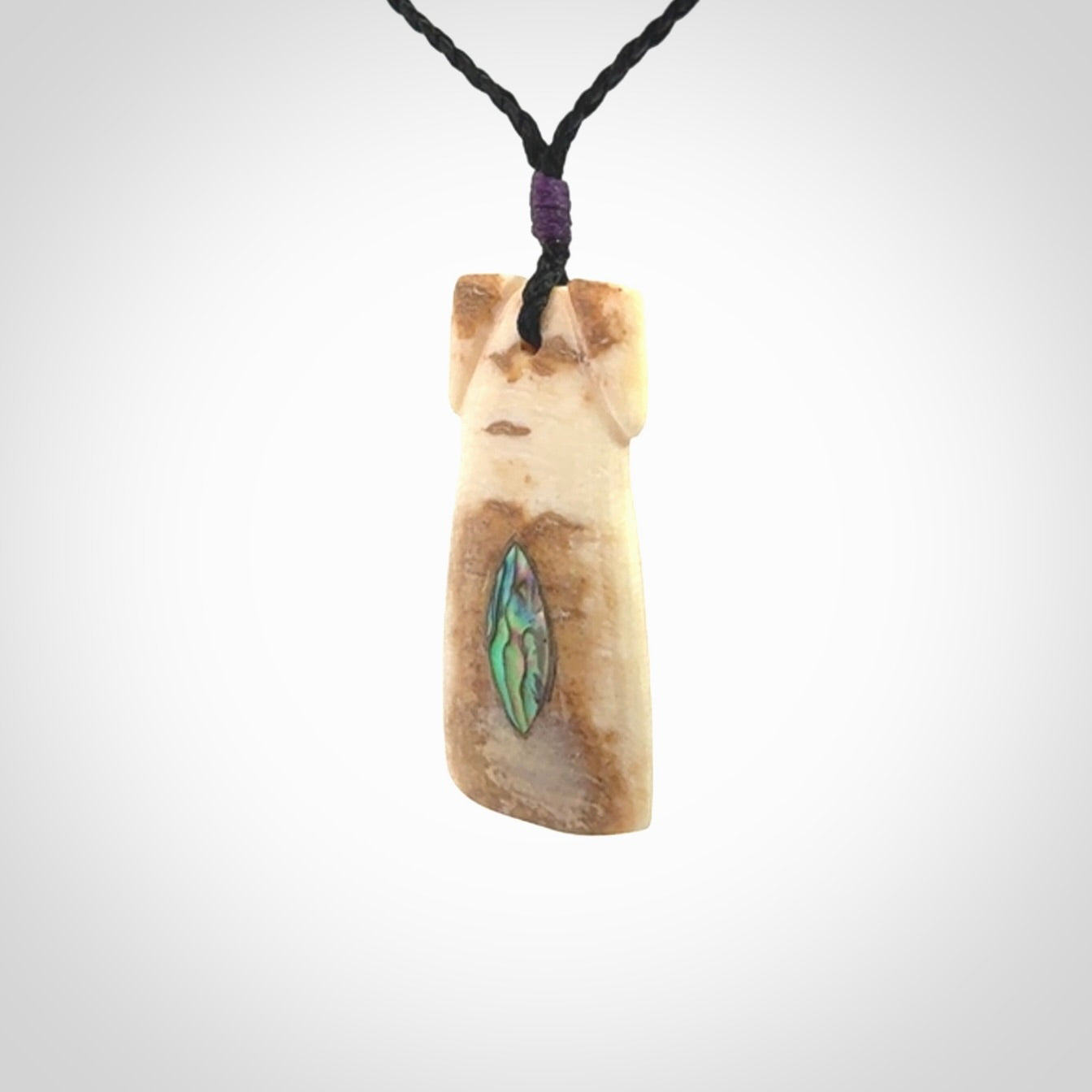 A stunning hand carved Woolly Mammoth Tusk Toki pendant. The toki has a small oval shaped piece of Pāua shell inset into the front face. This piece is bound with an adjustable cord. This is a little piece of Art to wear.