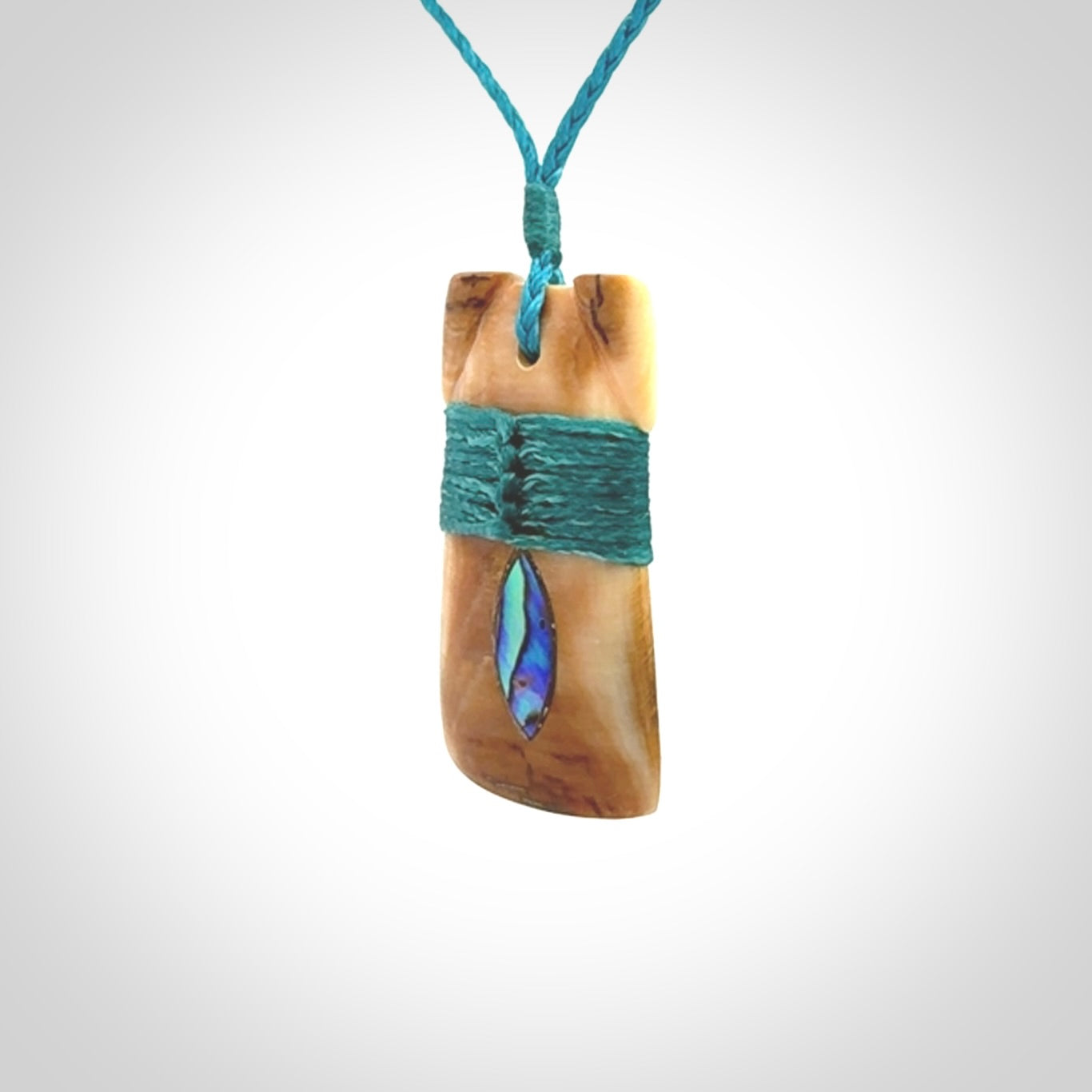 A stunning hand carved Woolly Mammoth Tusk Toki pendant. The toki has a small oval shaped piece of Pāua shell inset into the front face. This piece is bound with an adjustable cord. This is a little piece of Art to wear.