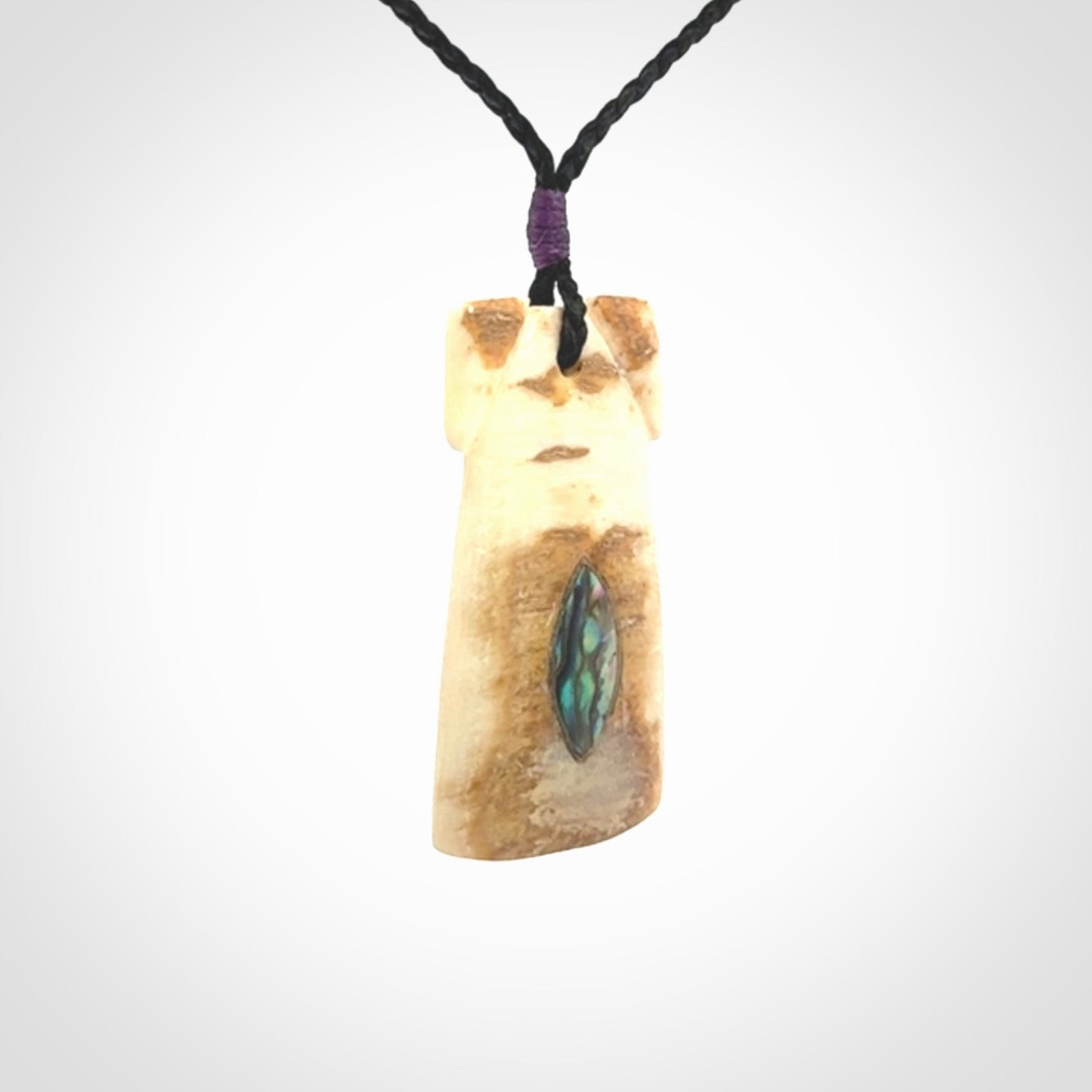 A stunning hand carved Woolly Mammoth Tusk Toki pendant. The toki has a small oval shaped piece of Pāua shell inset into the front face. This piece is bound with an adjustable cord. This is a little piece of Art to wear.