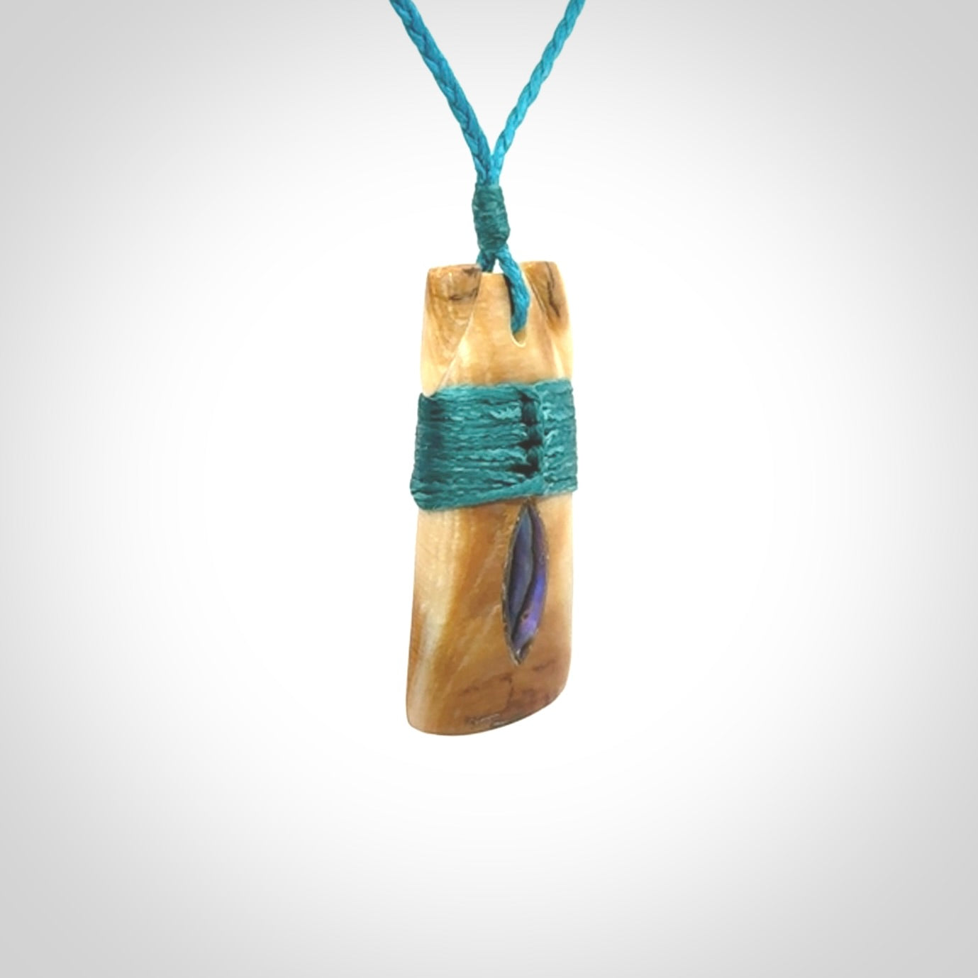 A stunning hand carved Woolly Mammoth Tusk Toki pendant. The toki has a small oval shaped piece of Pāua shell inset into the front face. This piece is bound with an adjustable cord. This is a little piece of Art to wear.