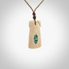 A stunning hand carved Woolly Mammoth Tusk Toki pendant. The toki has a small oval shaped piece of Pāua shell inset into the front face. This piece is bound with an adjustable cord. This is a little piece of Art to wear.