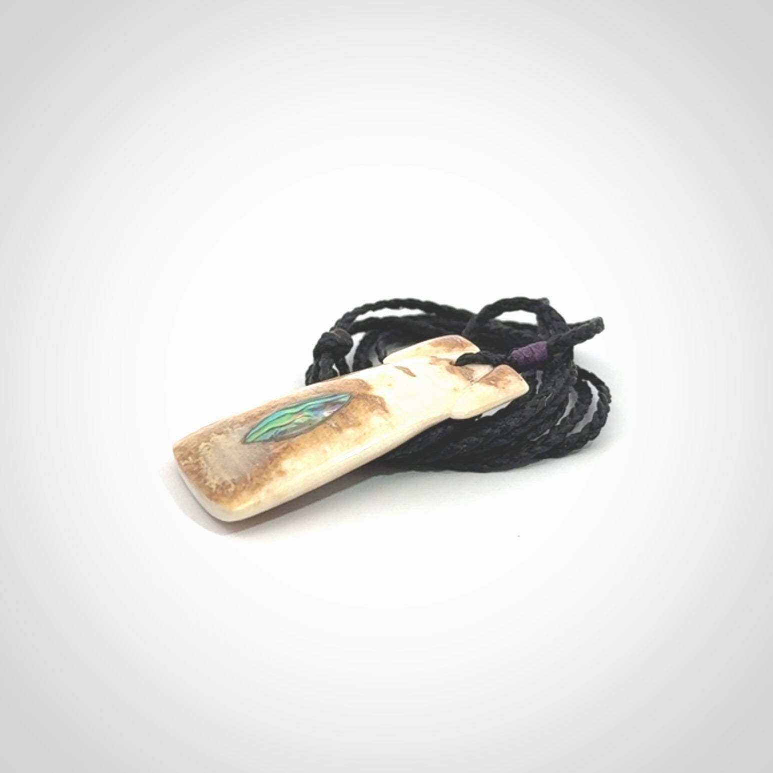A stunning hand carved Woolly Mammoth Tusk Toki pendant. The toki has a small oval shaped piece of Pāua shell inset into the front face. This piece is bound with an adjustable cord. This is a little piece of Art to wear.