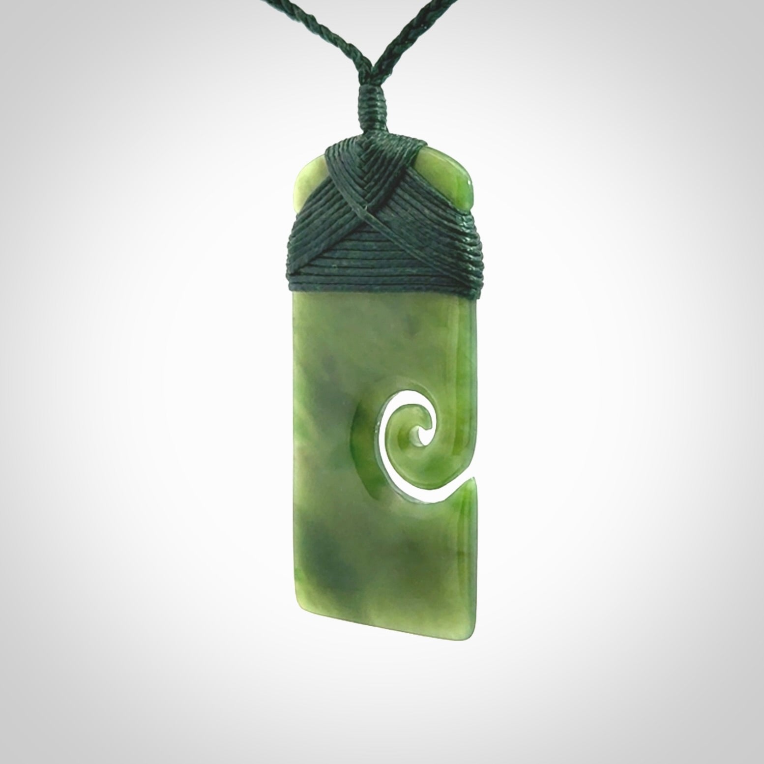British Coloumbian jade toki koru pendant. Hand carved in New Zealand. Hand made British Coloumbian Jade jewellery. Provided with an adjustable cord and packaged in a woven kete pouch.