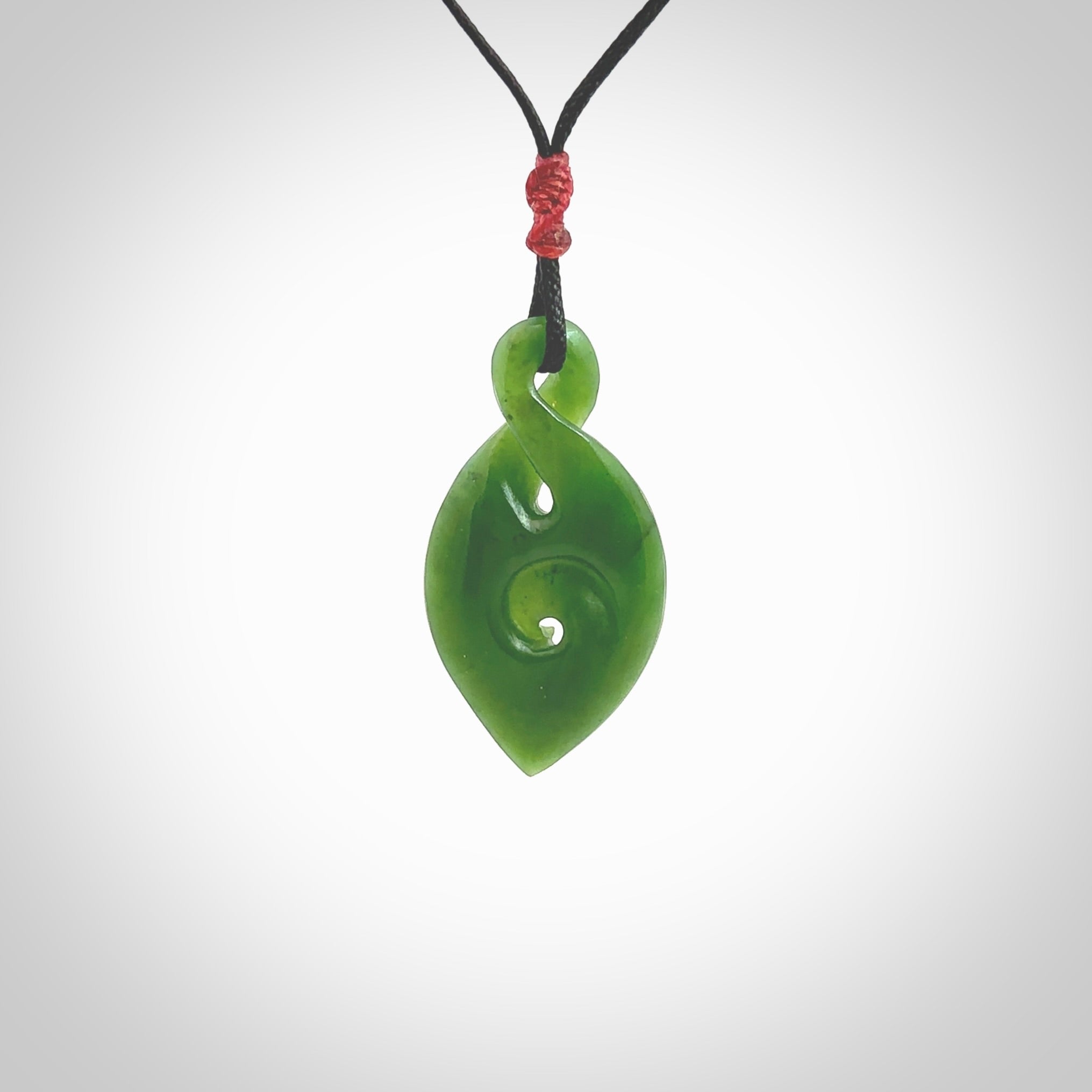 Ross Crump twist with koru pendant. Hand carved from rare New Zealand jade this is a beautiful pounamu pendant. The cord is hand plaited and is length adjustable. It has a little spiral floret popper at the top of the pendant. It is a delicate and very beautiful greenstone pendant. For sale online by NZ Pacific.