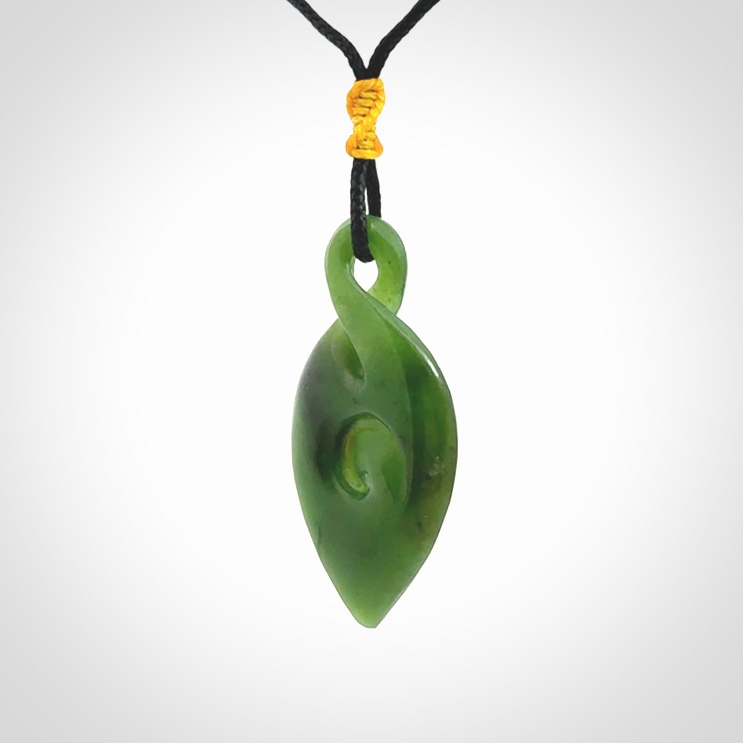 Ross Crump twist with koru pendant. Hand carved from rare New Zealand jade this is a beautiful pounamu pendant. The cord is a black colour and is length adjustable. It has a little spiral floret popper at the top of the pendant. It is a delicate and very beautiful greenstone pendant. For sale online by NZ Pacific.