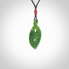 Ross Crump twist with koru pendant. Hand carved from rare New Zealand jade this is a beautiful pounamu pendant. The cord is hand plaited and is length adjustable. It has a little spiral floret popper at the top of the pendant. It is a delicate and very beautiful greenstone pendant. For sale online by NZ Pacific.