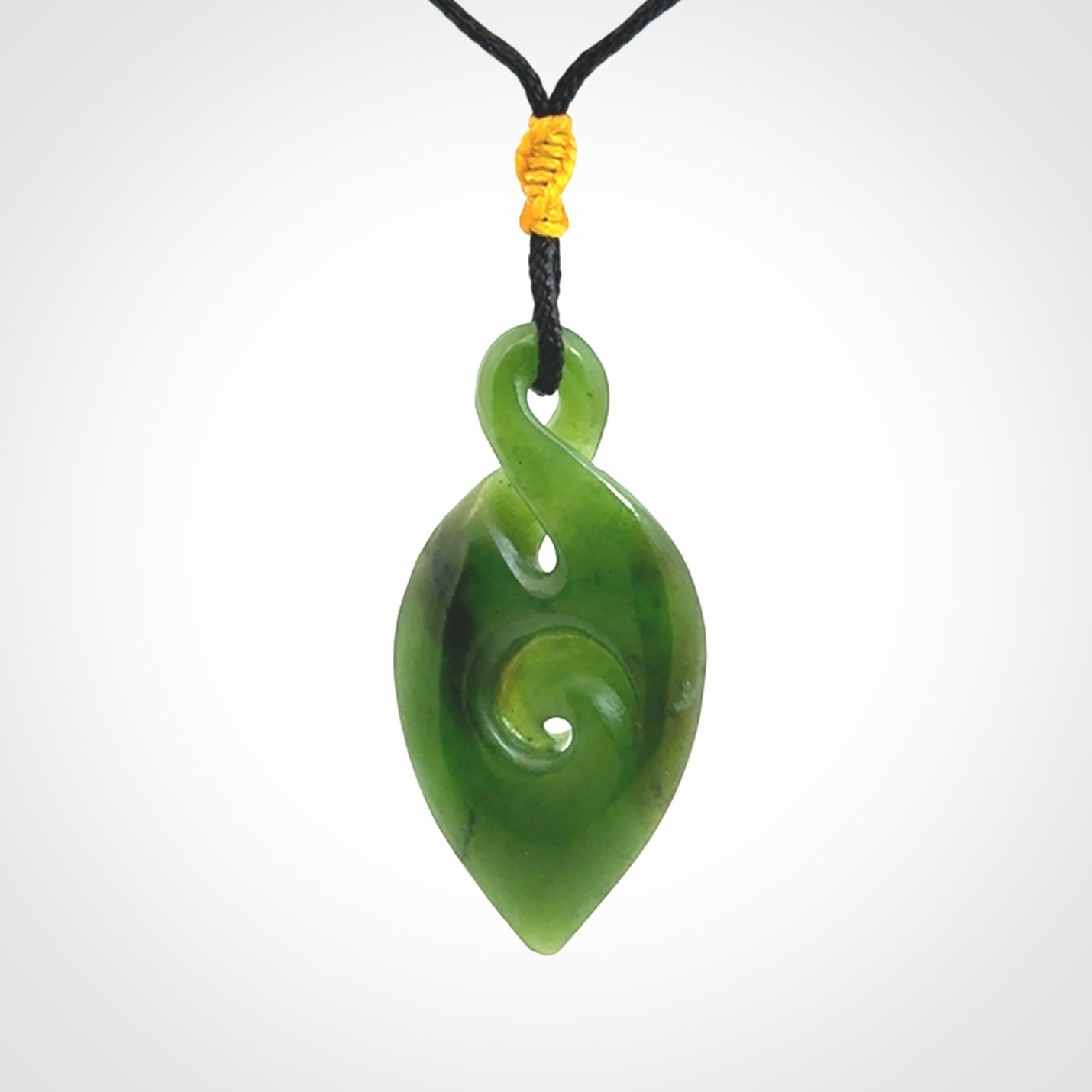 Ross Crump twist with koru pendant. Hand carved from rare New Zealand jade this is a beautiful pounamu pendant. The cord is a black colour and is length adjustable. It has a little spiral floret popper at the top of the pendant. It is a delicate and very beautiful greenstone pendant. For sale online by NZ Pacific.