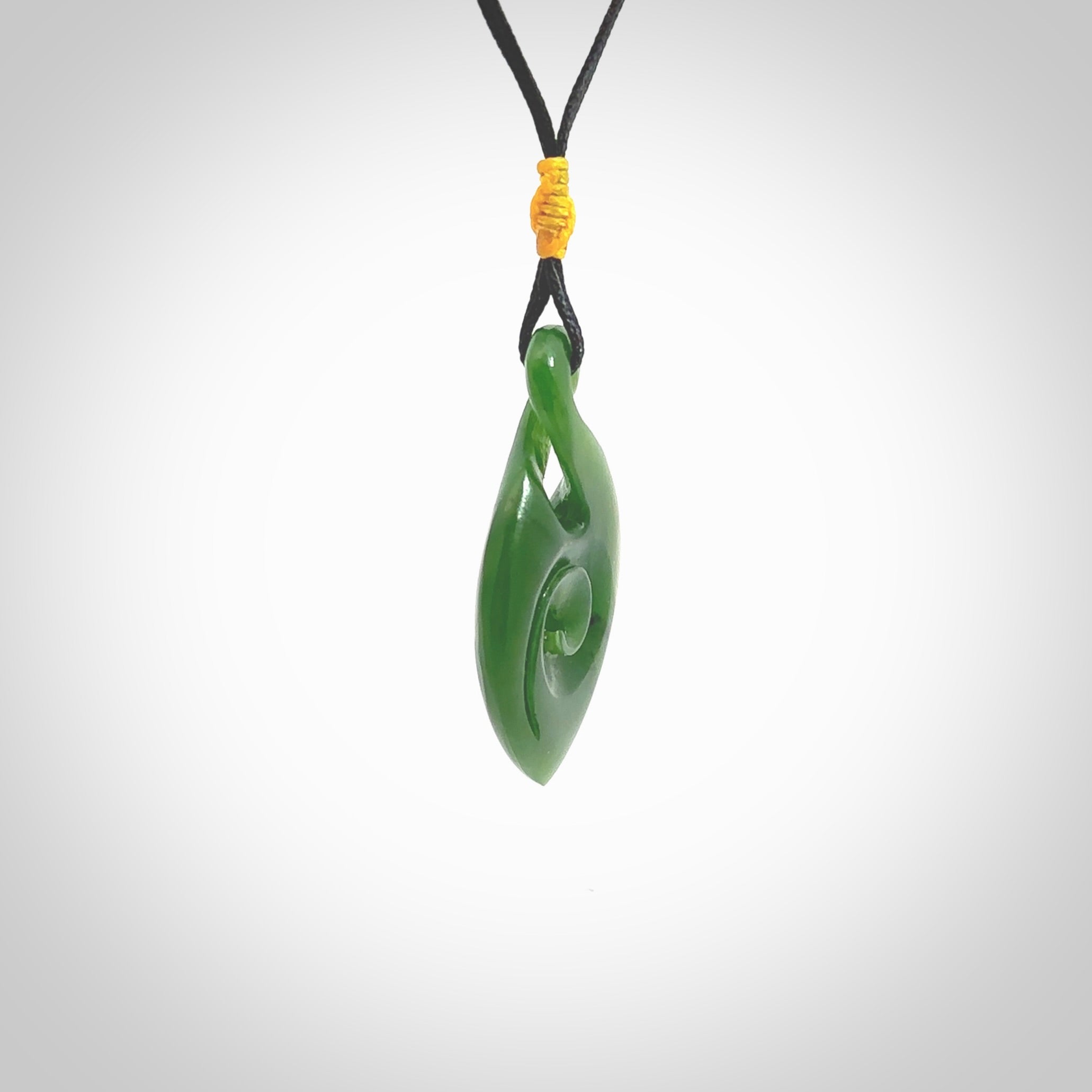 Ross Crump twist with koru pendant. Hand carved from rare New Zealand jade this is a beautiful pounamu pendant. The cord is hand plaited and is length adjustable. It has a little spiral floret popper at the top of the pendant. It is a delicate and very beautiful greenstone pendant. For sale online by NZ Pacific.