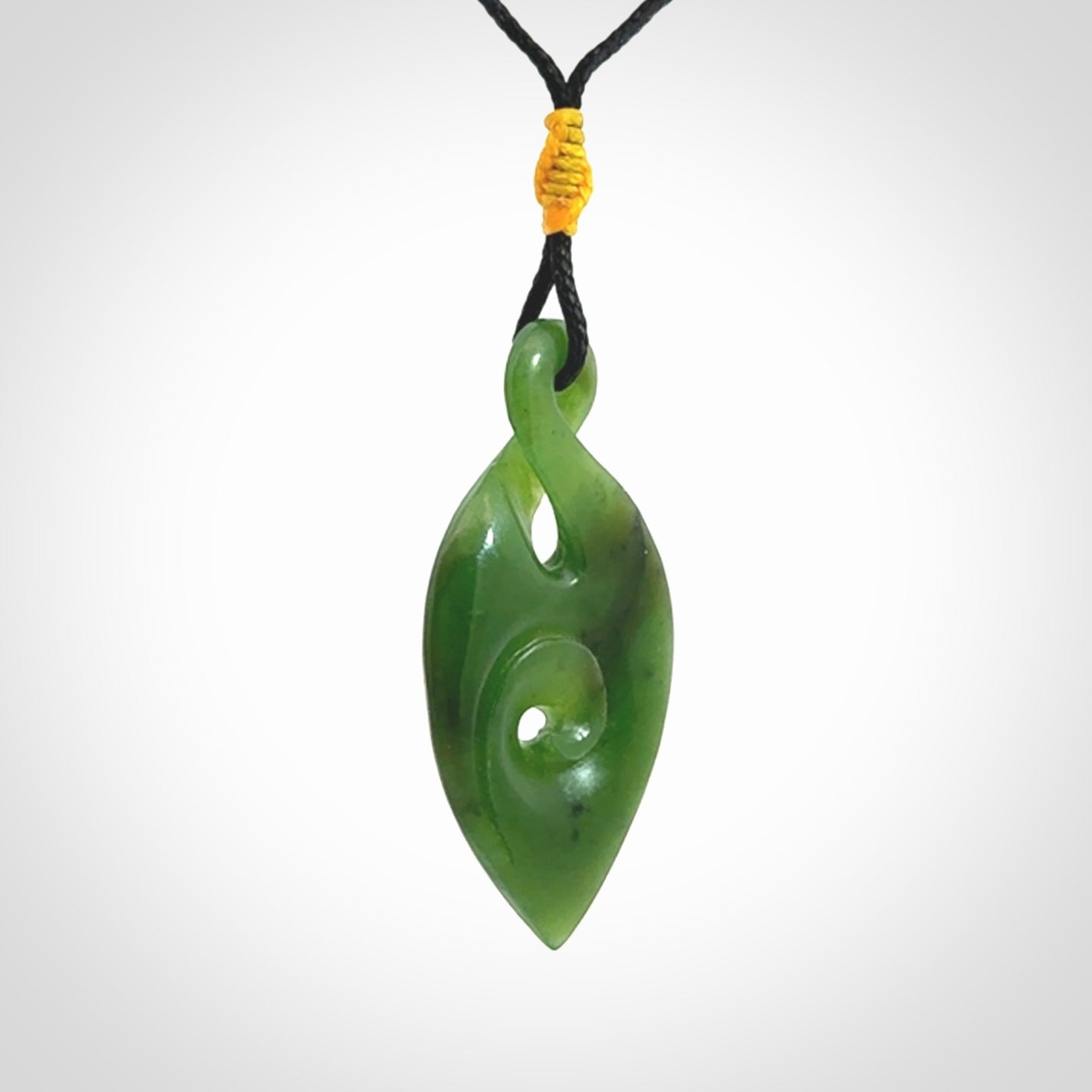 Ross Crump twist with koru pendant. Hand carved from rare New Zealand jade this is a beautiful pounamu pendant. The cord is a black colour and is length adjustable. It has a little spiral floret popper at the top of the pendant. It is a delicate and very beautiful greenstone pendant. For sale online by NZ Pacific.