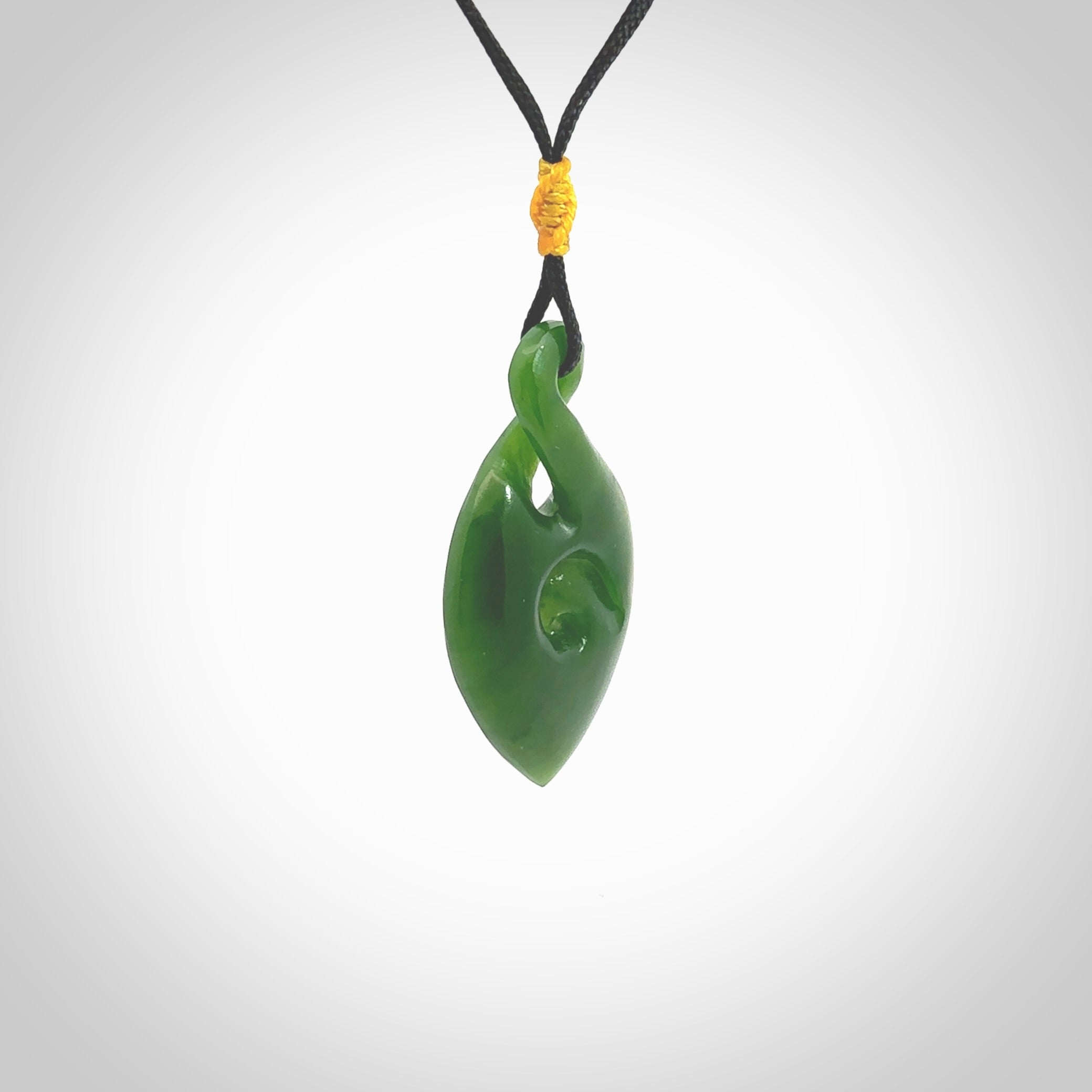 Ross Crump twist with koru pendant. Hand carved from rare New Zealand jade this is a beautiful pounamu pendant. The cord is hand plaited and is length adjustable. It has a little spiral floret popper at the top of the pendant. It is a delicate and very beautiful greenstone pendant. For sale online by NZ Pacific.