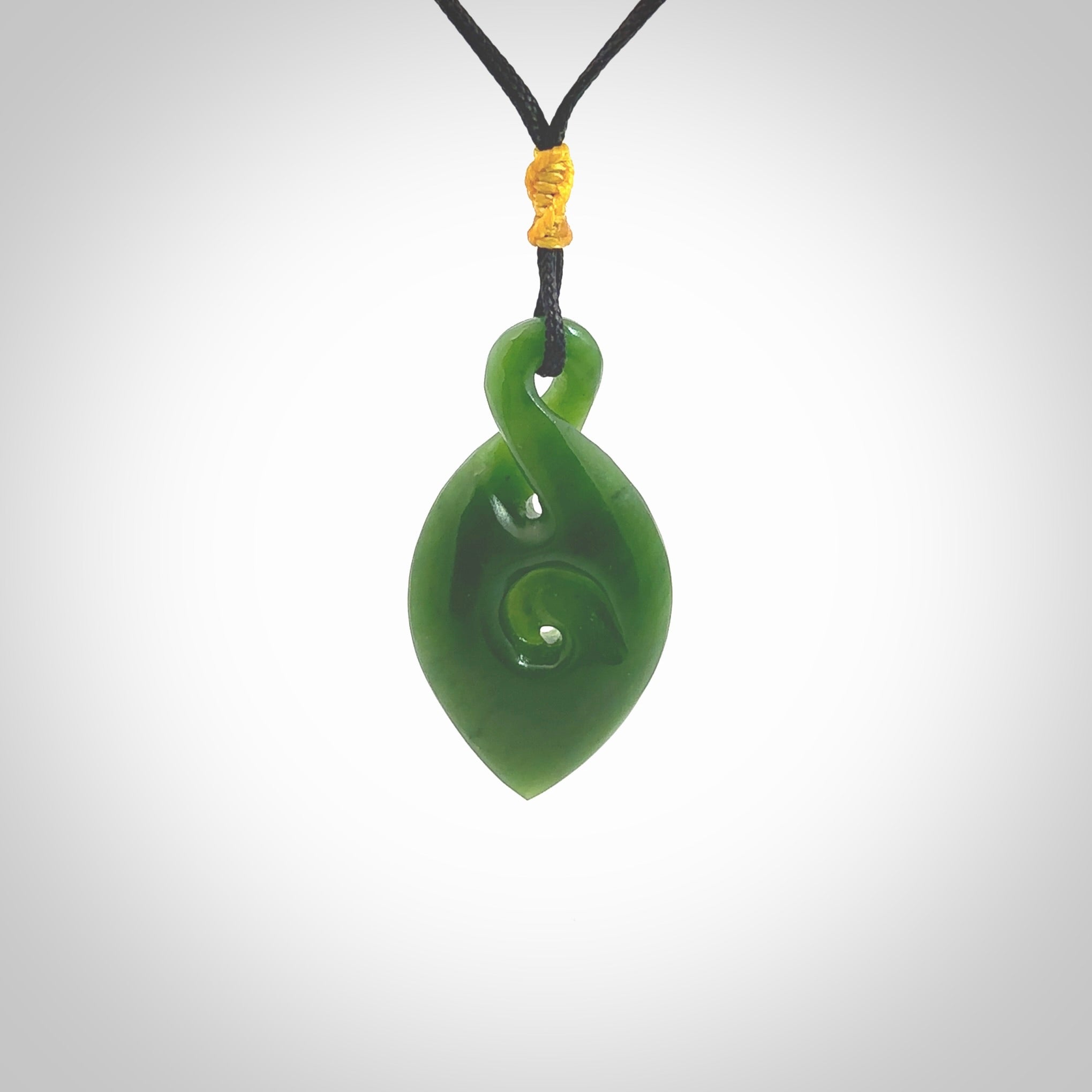 Ross Crump twist with koru pendant. Hand carved from rare New Zealand jade this is a beautiful pounamu pendant. The cord is hand plaited and is length adjustable. It has a little spiral floret popper at the top of the pendant. It is a delicate and very beautiful greenstone pendant. For sale online by NZ Pacific.