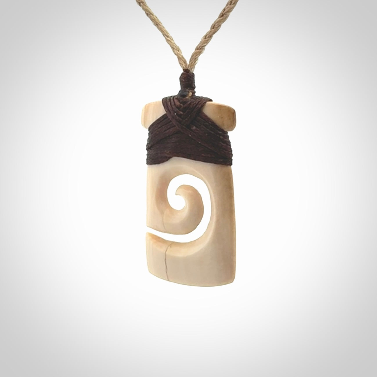 Hand carved Woolly Mammoth Tusk toki with koru pendant. Toki with koru necklace carved from ancient woolly mammoth tusk. Provided with adjustable cord and packaged in a woven kete pouch.