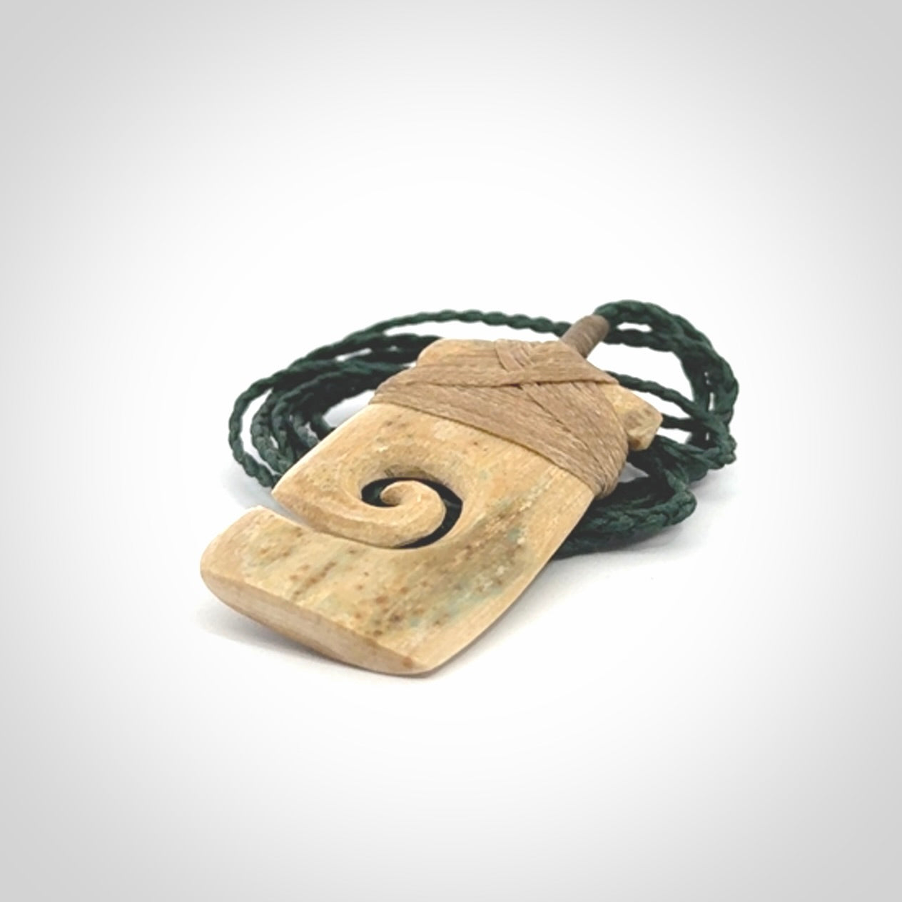 Hand carved Woolly Mammoth Tusk toki with koru pendant. Toki with koru necklace carved from ancient woolly mammoth tusk. Provided with adjustable cord and packaged in a woven kete pouch.