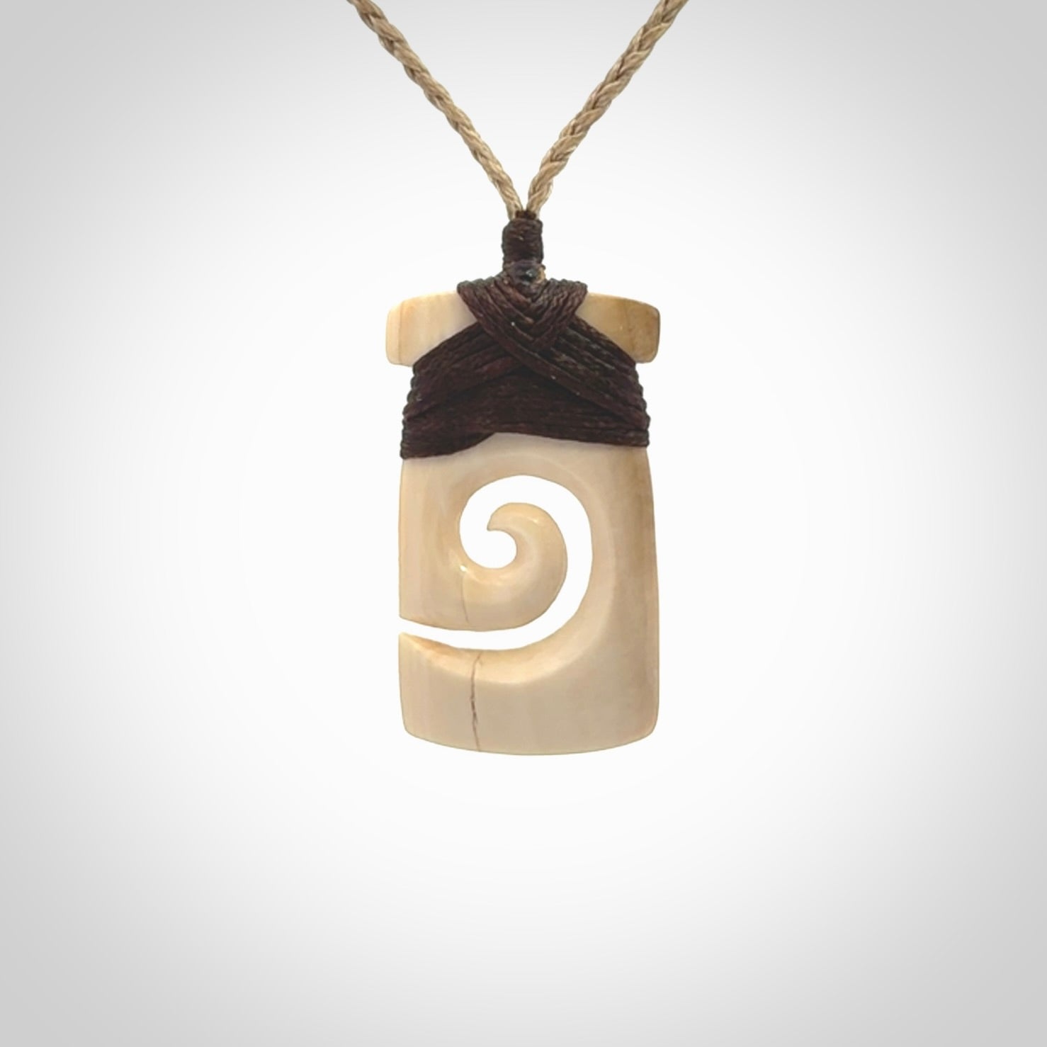 Hand carved Woolly Mammoth Tusk toki with koru pendant. Toki with koru necklace carved from ancient woolly mammoth tusk. Provided with adjustable cord and packaged in a woven kete pouch.
