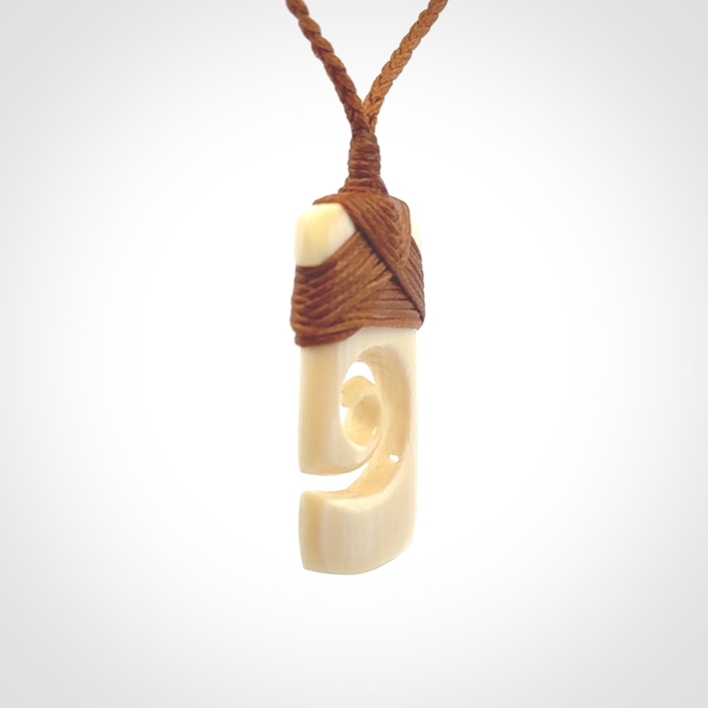 Hand carved Woolly Mammoth Tusk toki with koru pendant. Toki with koru necklace carved from ancient woolly mammoth tusk. Provided with adjustable cord and packaged in a woven kete pouch.
