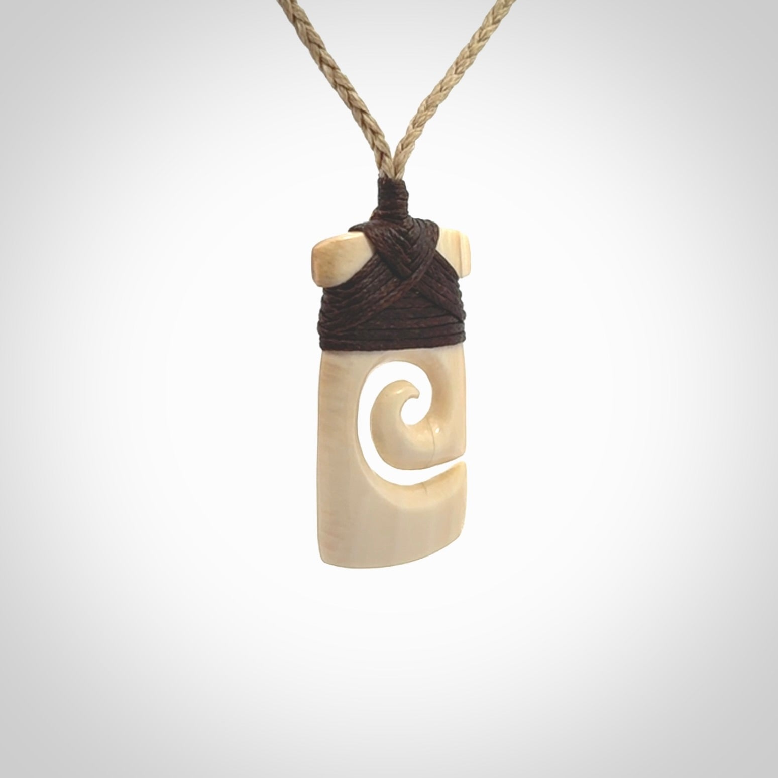 Hand carved Woolly Mammoth Tusk toki with koru pendant. Toki with koru necklace carved from ancient woolly mammoth tusk. Provided with adjustable cord and packaged in a woven kete pouch.