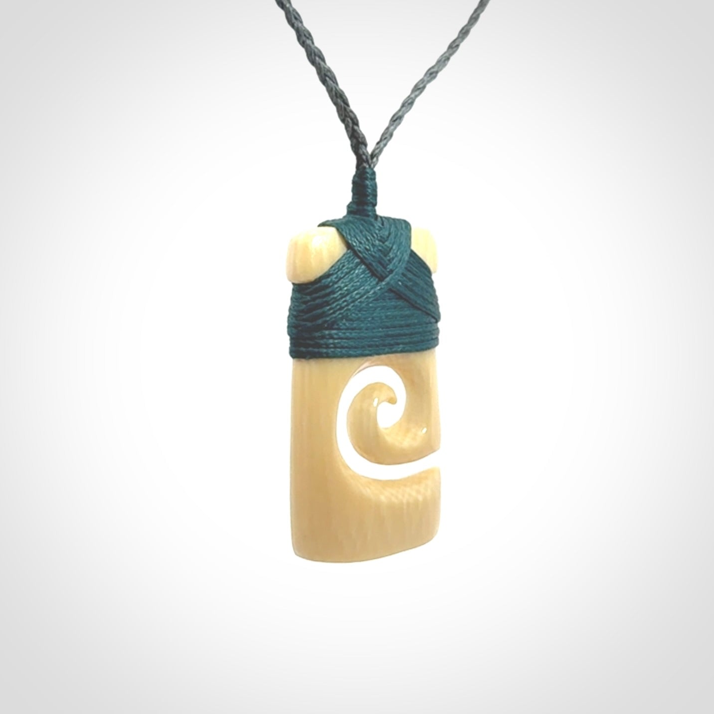 Hand carved Woolly Mammoth Tusk toki with koru pendant. Toki with koru necklace carved from ancient woolly mammoth tusk. Provided with adjustable cord and packaged in a woven kete pouch.