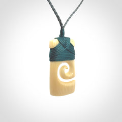 Hand carved Woolly Mammoth Tusk toki with koru pendant. Toki with koru necklace carved from ancient woolly mammoth tusk. Provided with adjustable cord and packaged in a woven kete pouch.