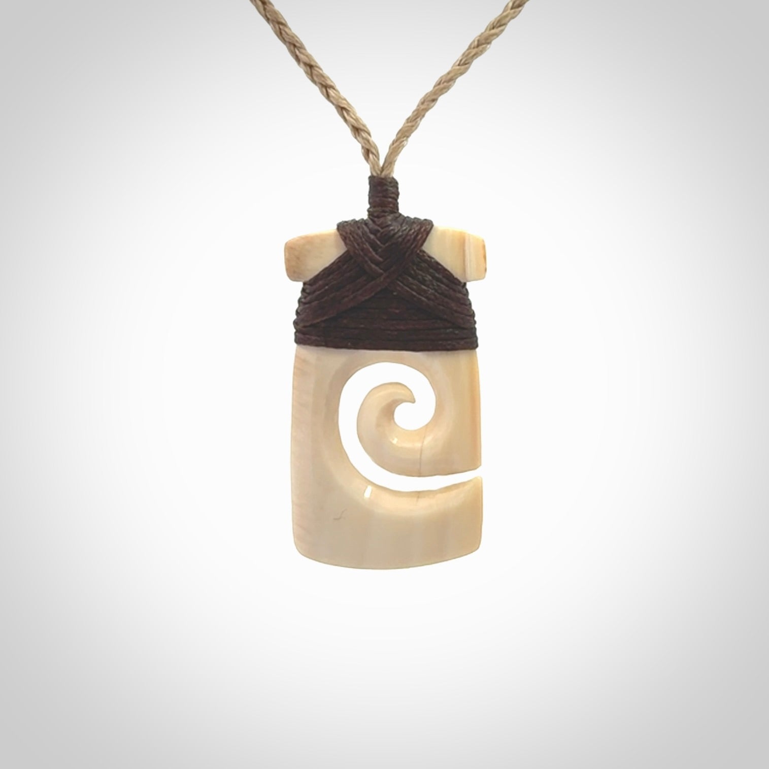 Hand carved Woolly Mammoth Tusk toki with koru pendant. Toki with koru necklace carved from ancient woolly mammoth tusk. Provided with adjustable cord and packaged in a woven kete pouch.