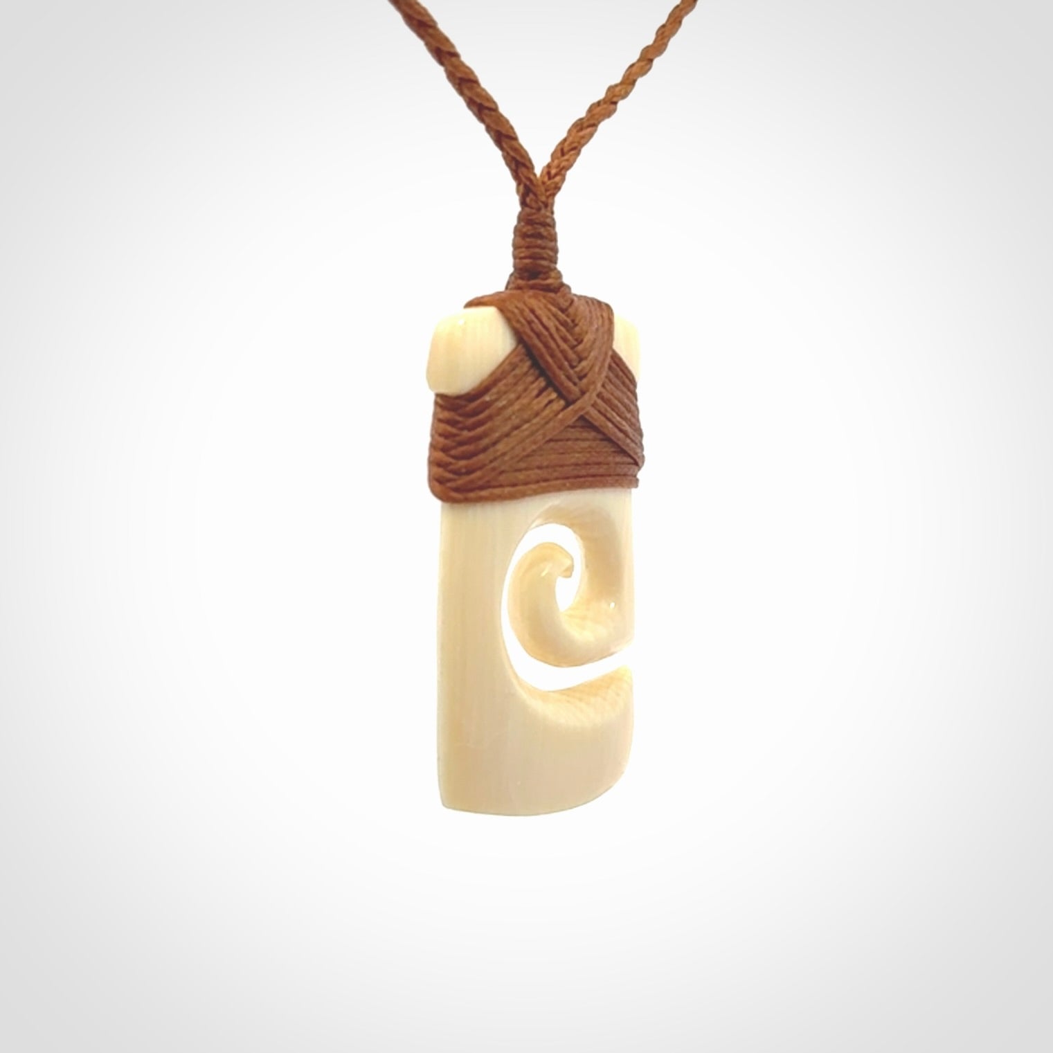 Hand carved Woolly Mammoth Tusk toki with koru pendant. Toki with koru necklace carved from ancient woolly mammoth tusk. Provided with adjustable cord and packaged in a woven kete pouch.