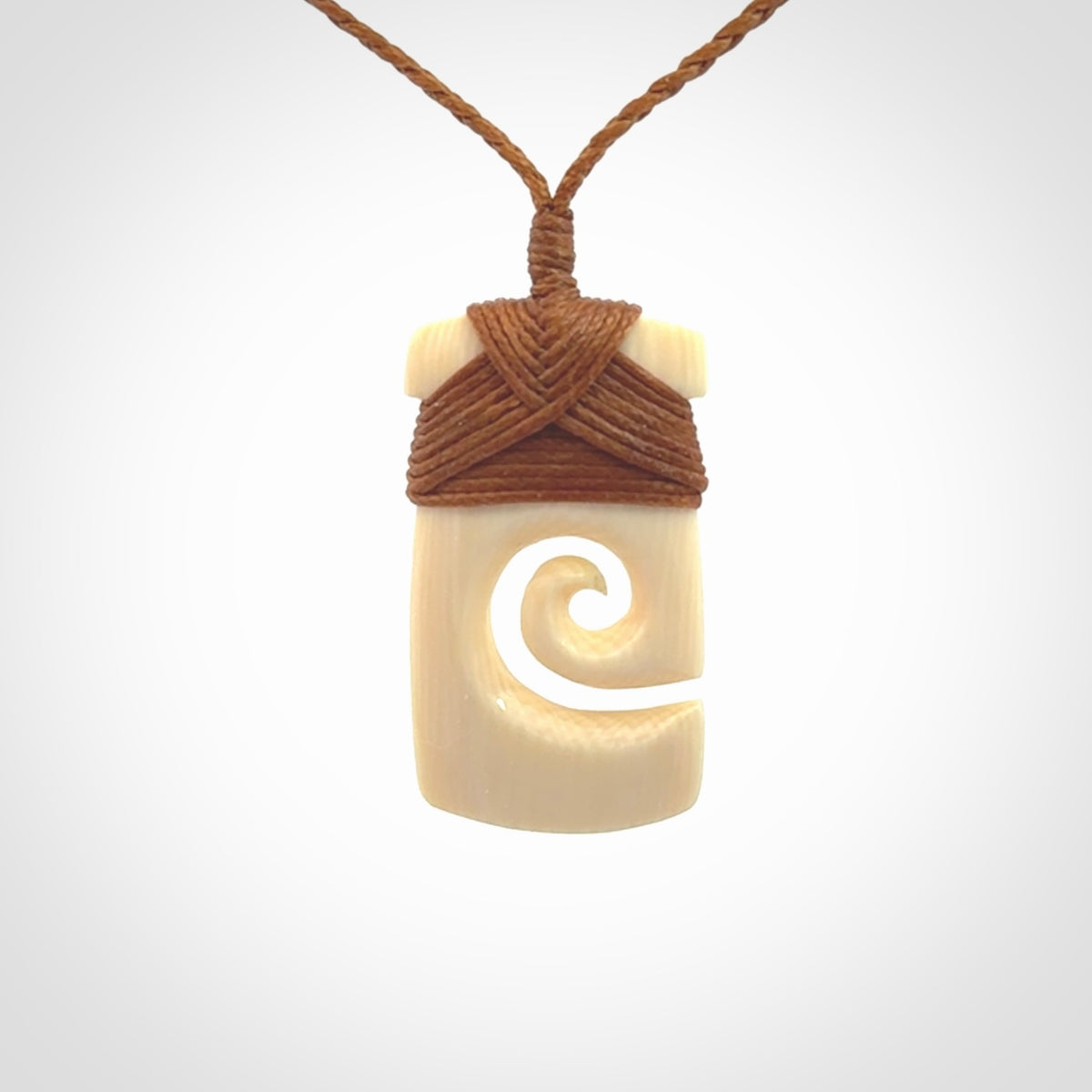 Hand carved Woolly Mammoth Tusk toki with koru pendant. Toki with koru necklace carved from ancient woolly mammoth tusk. Provided with adjustable cord and packaged in a woven kete pouch.