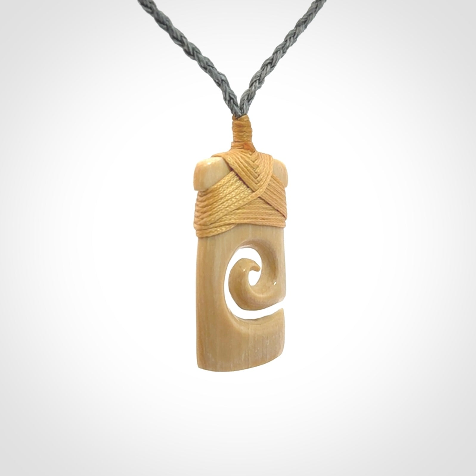 Hand carved Woolly Mammoth Tusk toki with koru pendant. Toki with koru necklace carved from ancient woolly mammoth tusk. Provided with adjustable cord and packaged in a woven kete pouch.