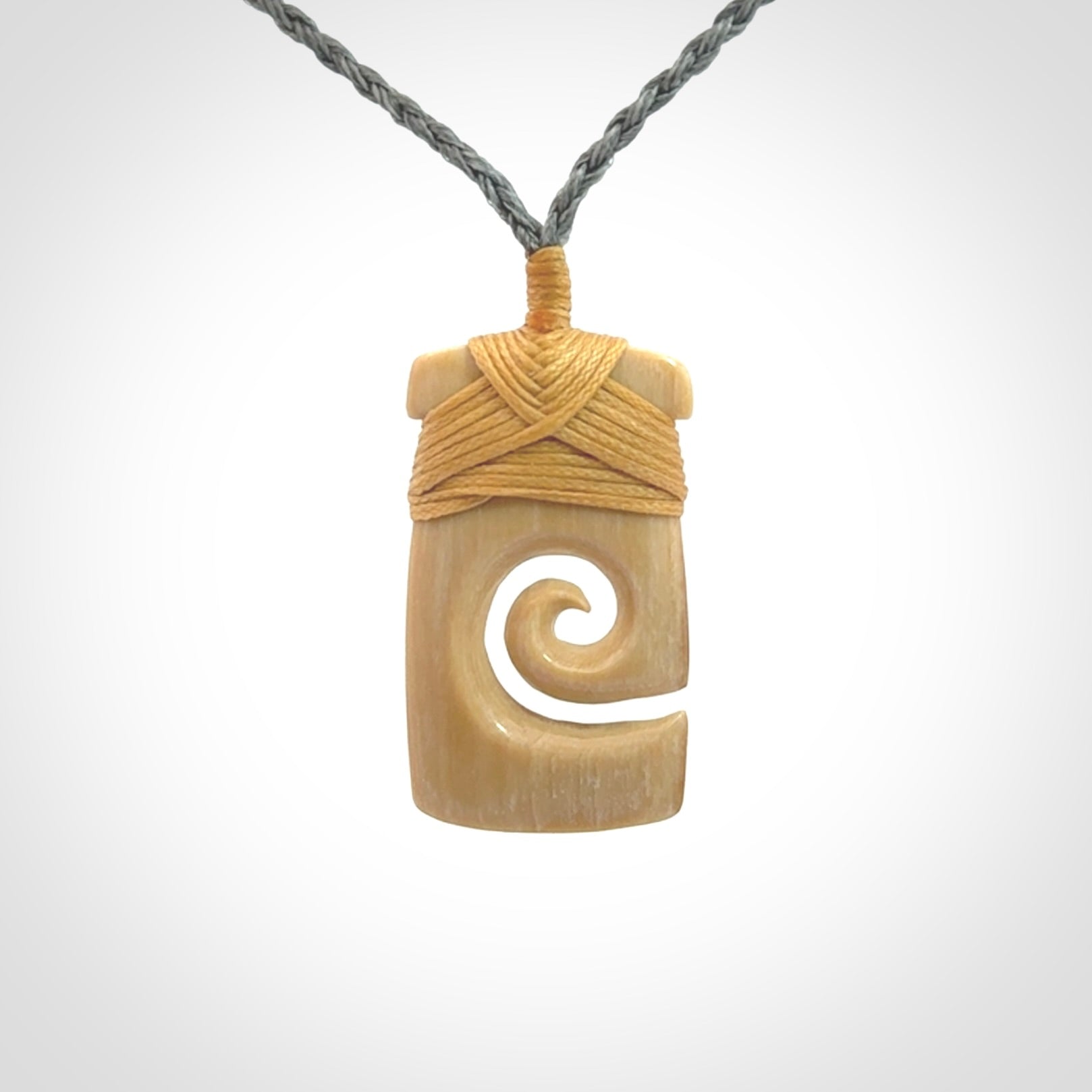 Hand carved Woolly Mammoth Tusk toki with koru pendant. Toki with koru necklace carved from ancient woolly mammoth tusk. Provided with adjustable cord and packaged in a woven kete pouch.