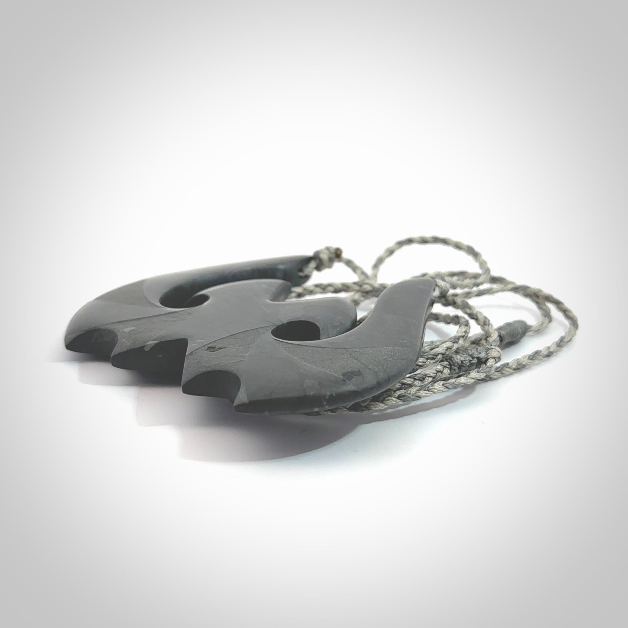 A hand carved large New Zealand Argillite double Hook, Matau, necklace. The cord is a black colour and is adjustable in length. A large sized hand made double hook necklace by New Zealand artist Rueben Tipene. One off work of art to wear.