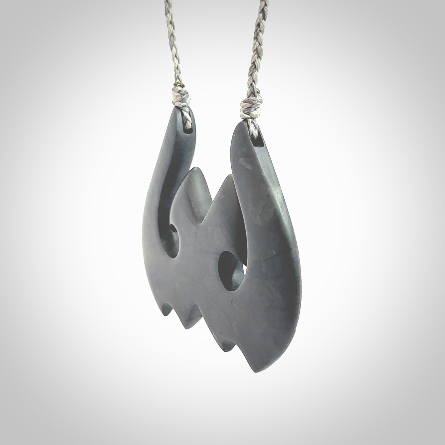 A hand carved large New Zealand Argillite double Hook, Matau, necklace. The cord is a black colour and is adjustable in length. A large sized hand made double hook necklace by New Zealand artist Rueben Tipene. One off work of art to wear.