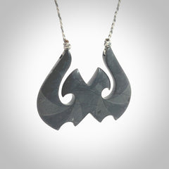 A hand carved large New Zealand Argillite double Hook, Matau, necklace. The cord is a black colour and is adjustable in length. A large sized hand made double hook necklace by New Zealand artist Rueben Tipene. One off work of art to wear.