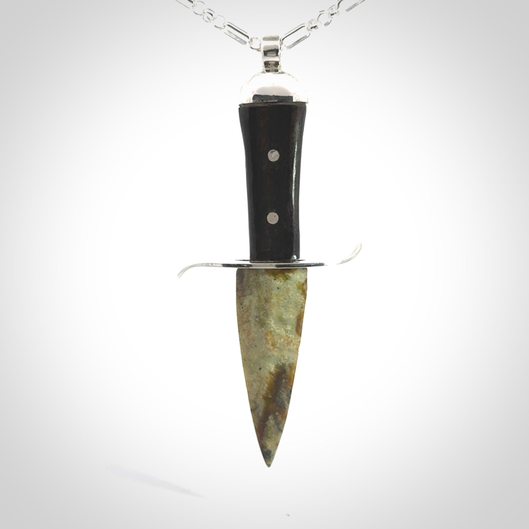 A striking hand carved knife pendant. These are carved with a green jade head and a hardwood handle. The necklace is sterling silver. We ship these worldwide with express courier.