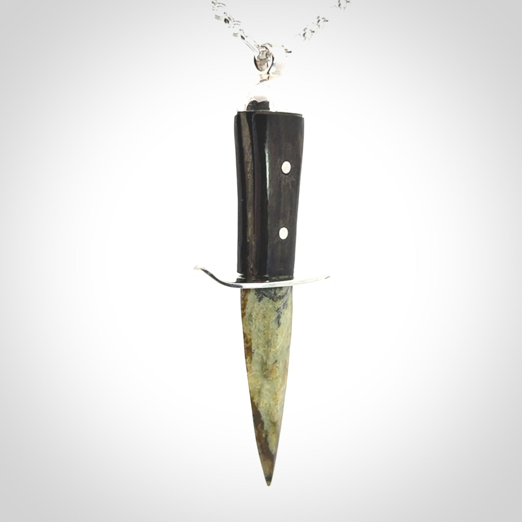 A striking hand carved knife pendant. These are carved with a green jade head and a hardwood handle. The necklace is sterling silver. We ship these worldwide with express courier.