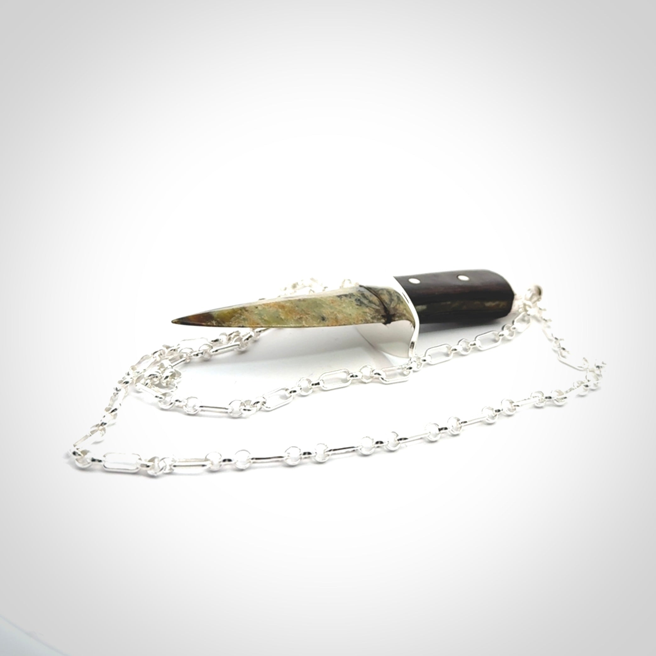 A striking hand carved knife pendant. These are carved with a green jade head and a hardwood handle. The necklace is sterling silver. We ship these worldwide with express courier.