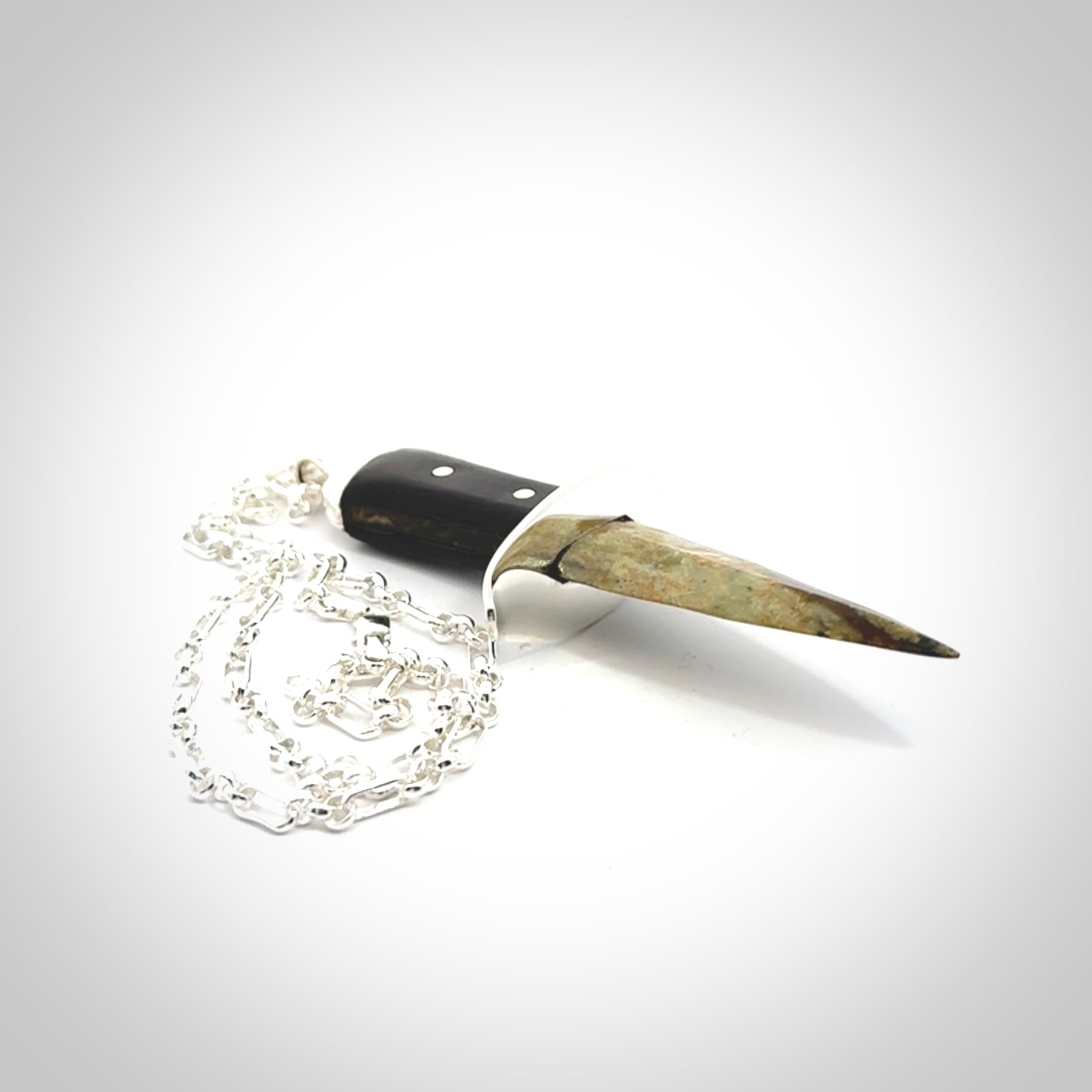 A striking hand carved knife pendant. These are carved with a green jade head and a hardwood handle. The necklace is sterling silver. We ship these worldwide with express courier.